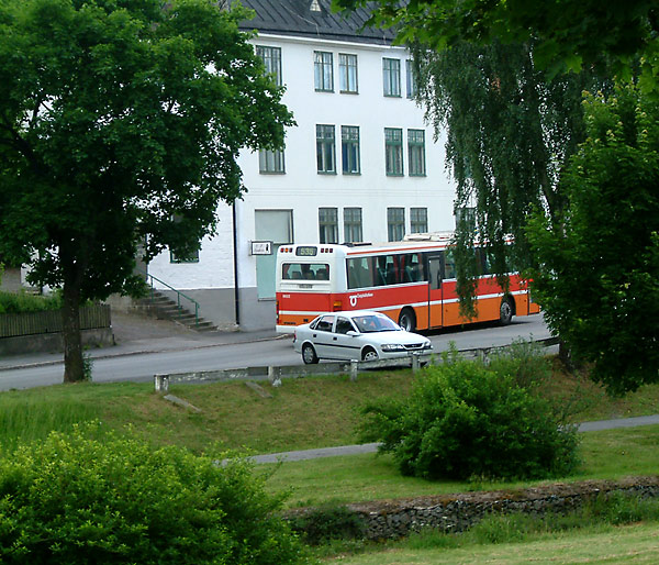 a bus going past an apartment building with trees around it