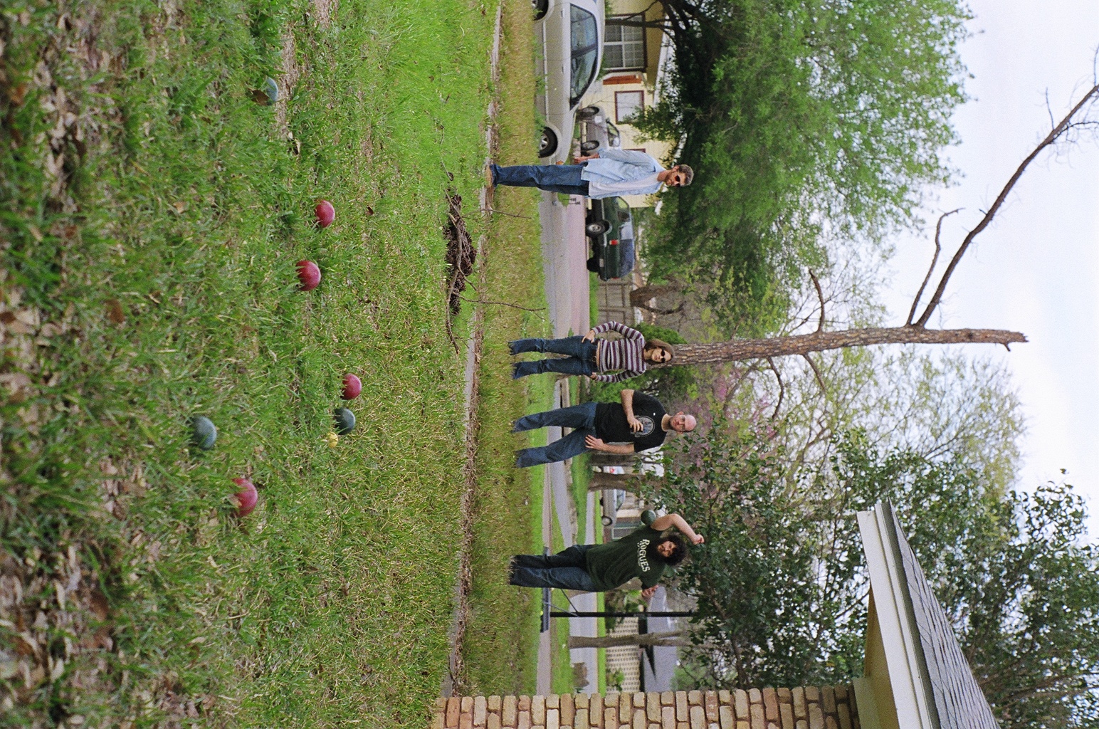 a group of people stand around in the grass near trees