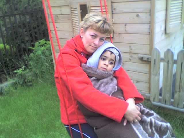 woman holding young child while sitting on the back of a swing