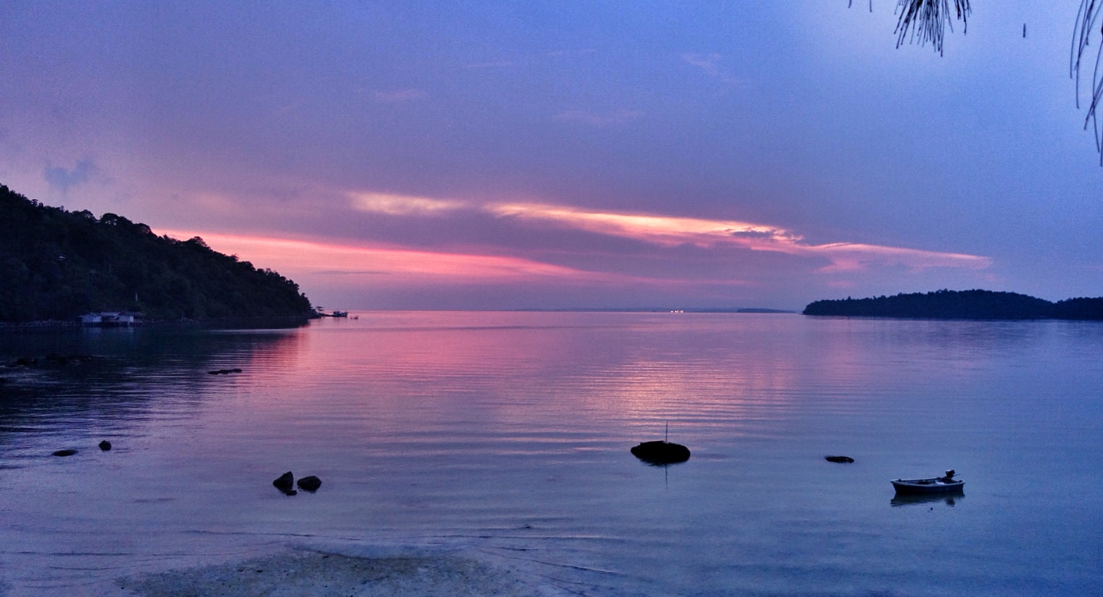 a sunset and boat on a water at a dock