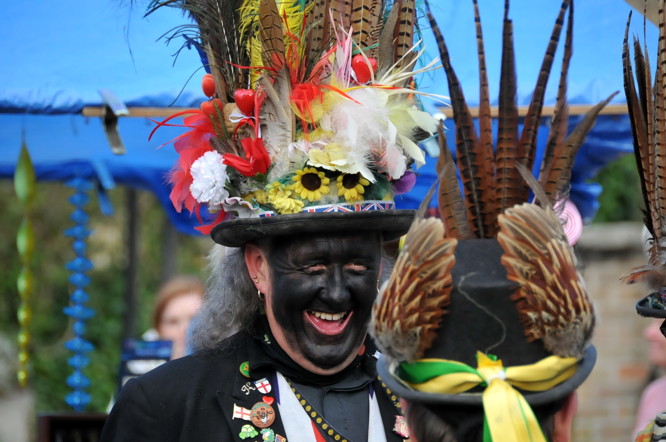 a man in a top hat smiles in front of some feathers