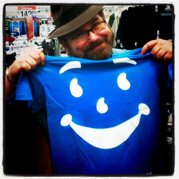a man holding up a smiling t shirt