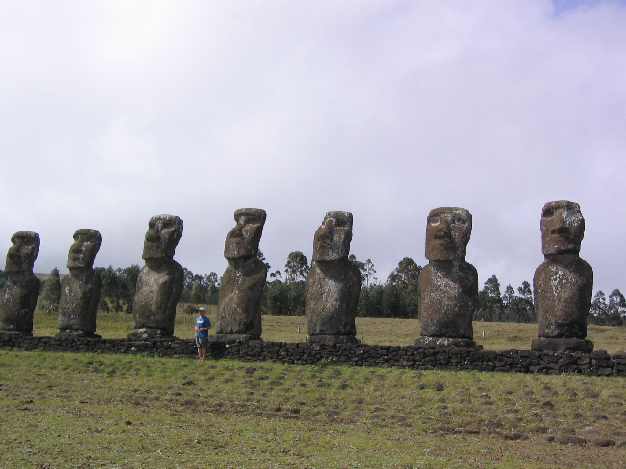 people standing around the giant statues in the field