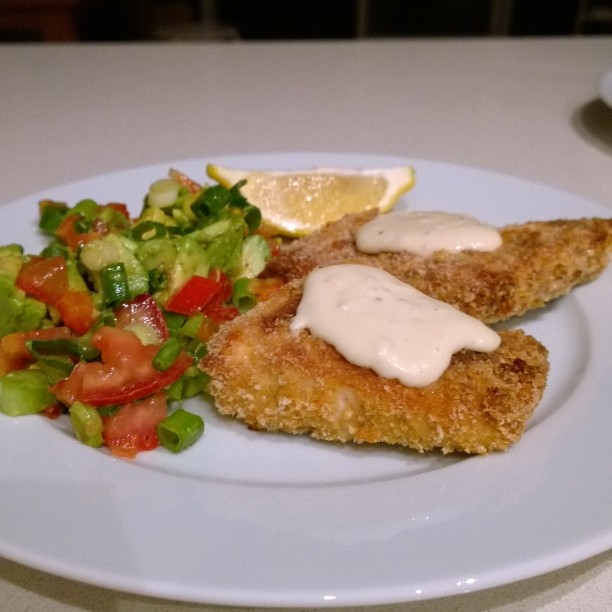 chicken tenders on a white plate with salad