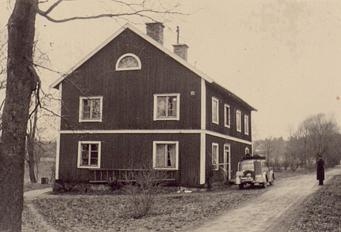 old picture of house with woman approaching the house