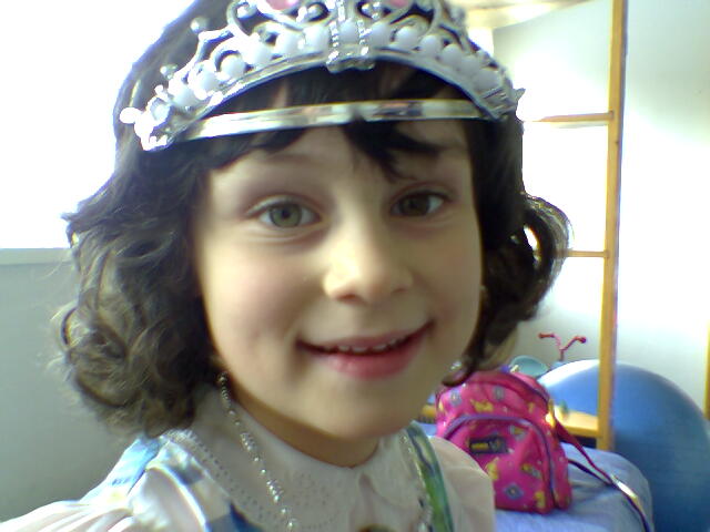 a  wearing a tiara and smiling at the camera