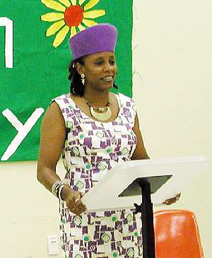 woman standing next to orange bags, in front of a green banner
