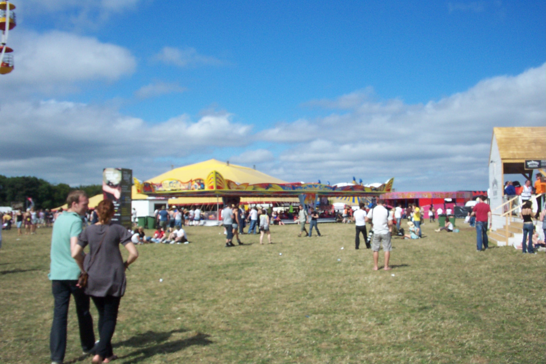 people flying a kite in a field full of tents