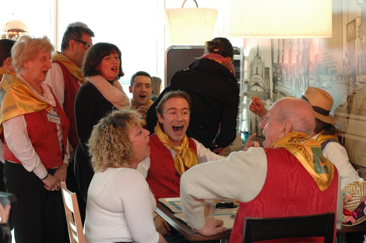 two women talking to a man in a red suit and a group of people