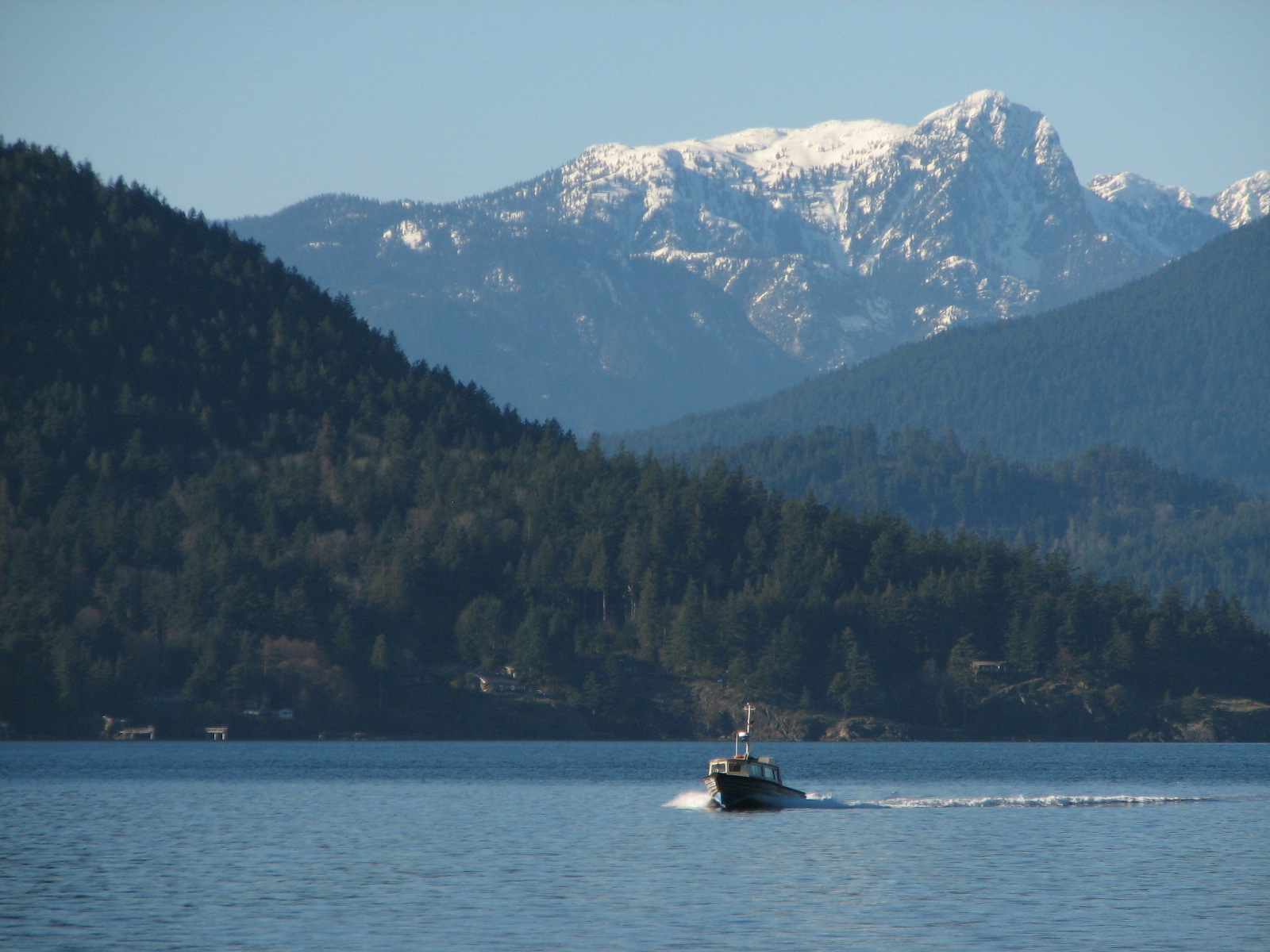 a boat traveling through a large body of water near some mountains