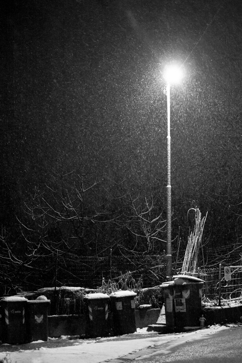 snow falling in the air and street light in background