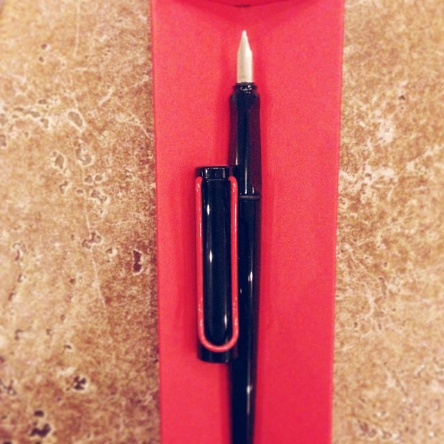 a red cardboard holder with a pen on it