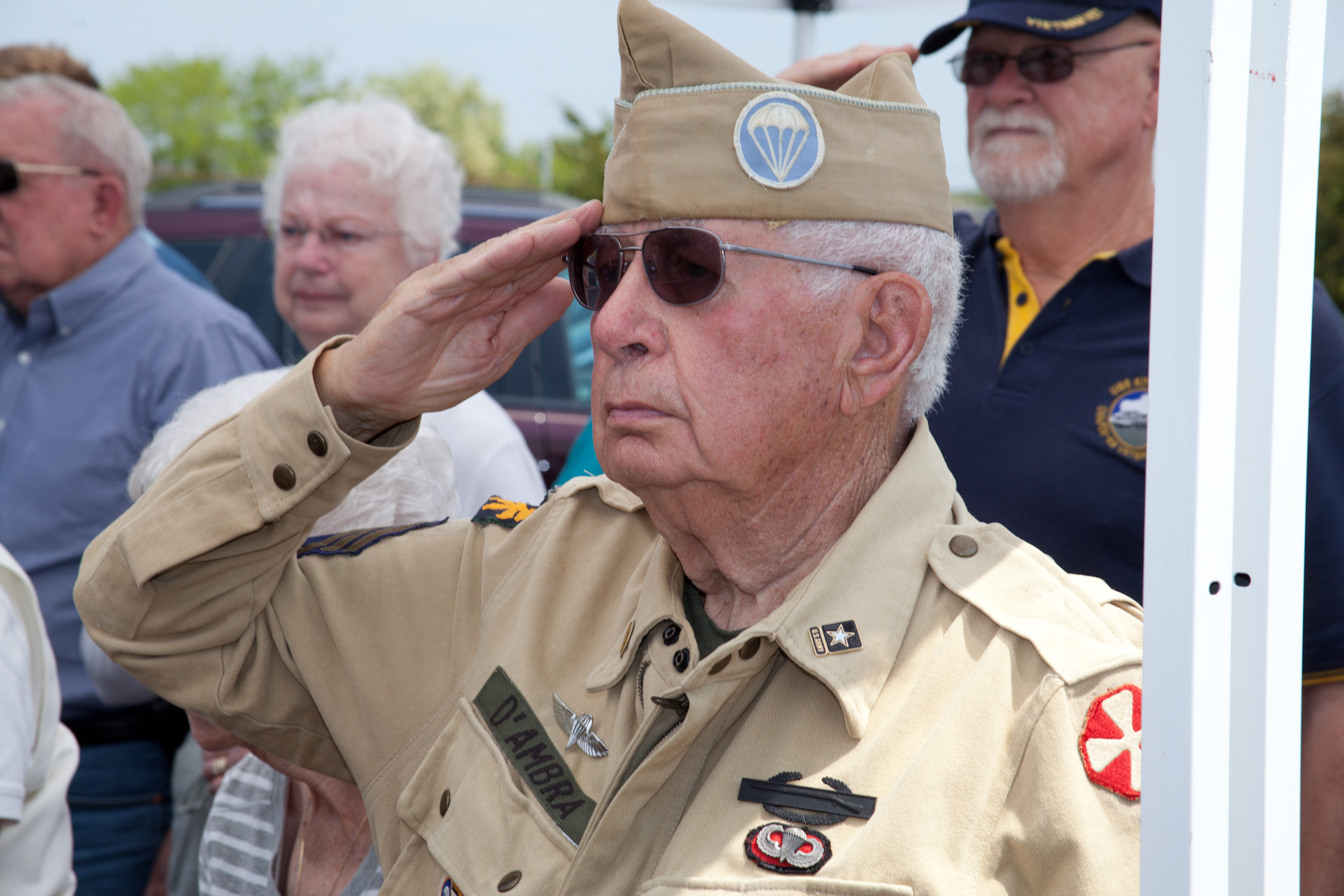 an old man dressed in army fatigues saluting people