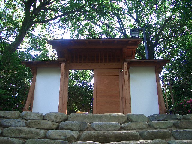 a wooden gate sitting between two stone walls and trees