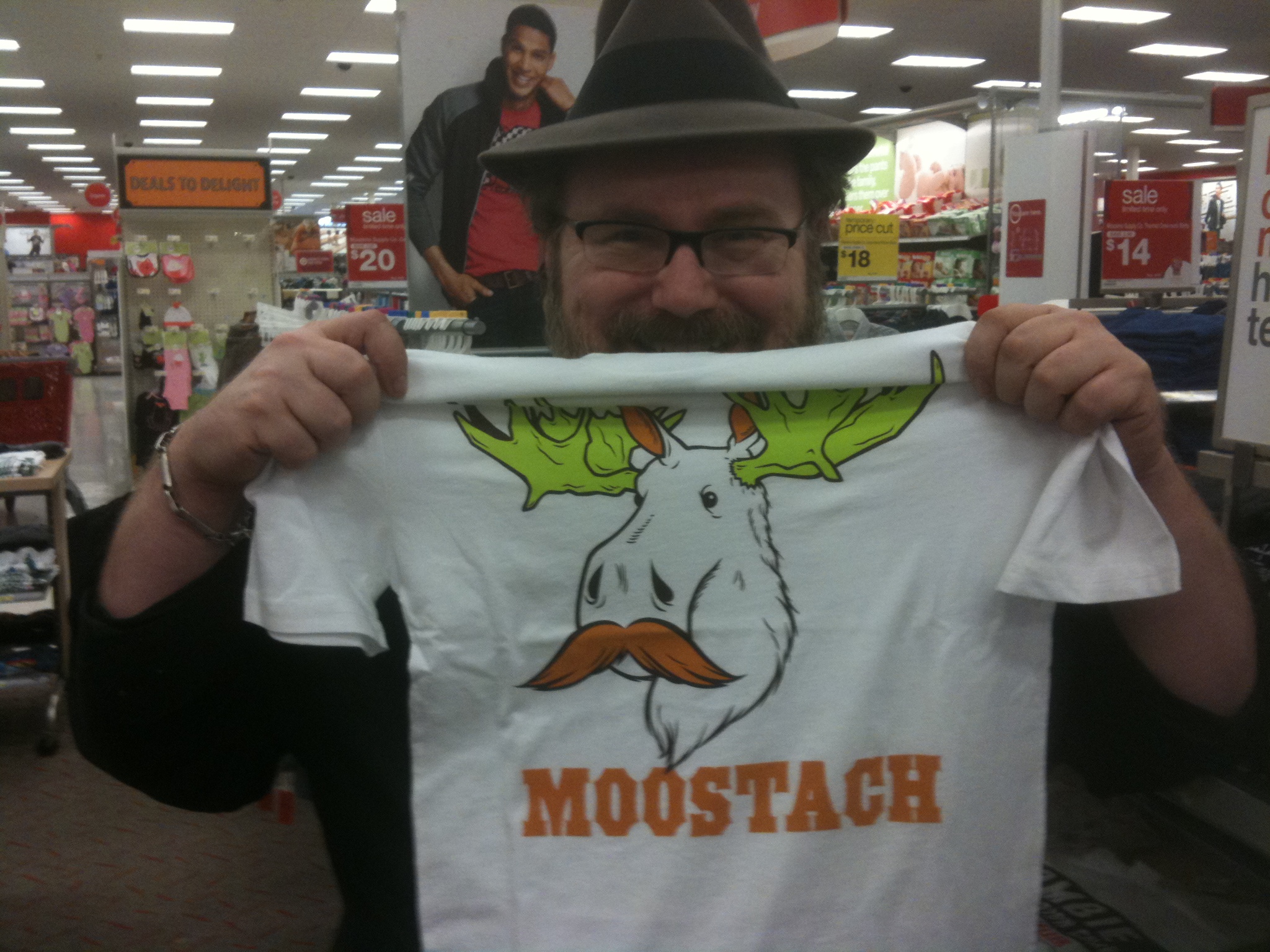 a man holding a moustache t - shirt in the store