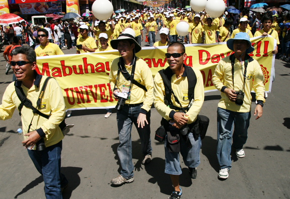 several people in yellow shirt and black hat marching down the street