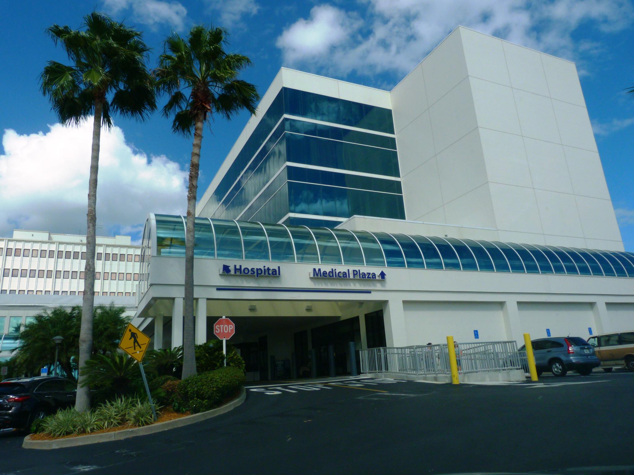 the front of an airport building with palm trees