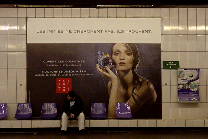 a man sits next to an advertit for a perfume