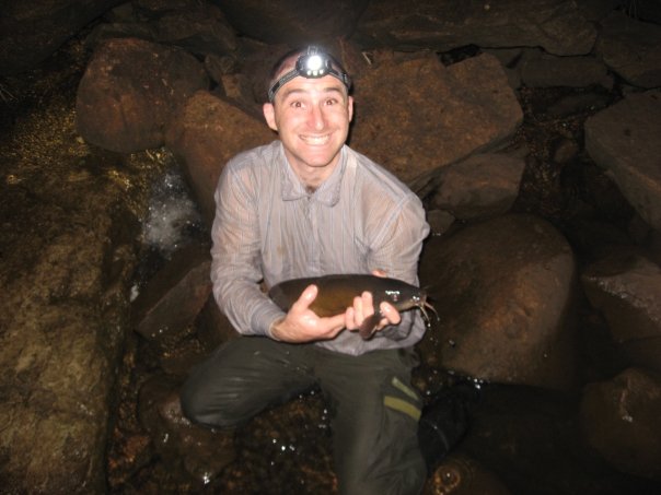 man holding up a fish in a cave