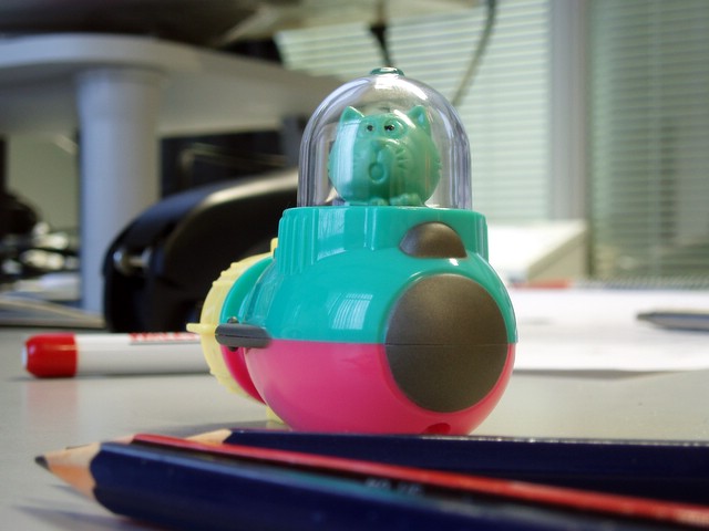 a toy in the shape of a ball sits next to pencils on a desk