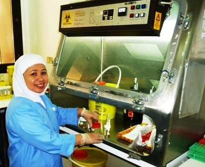 a woman in blue jacket washing some food in a fryer