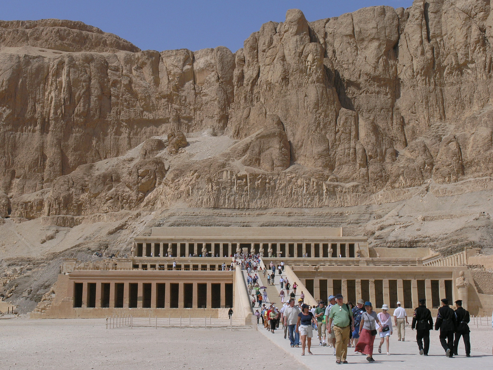 a group of people walking in front of an entrance to the egyptian temple