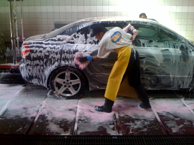 a person with a coat on, washing a car