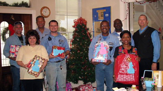 a group of people posing for a po with gifts in front of a christmas tree