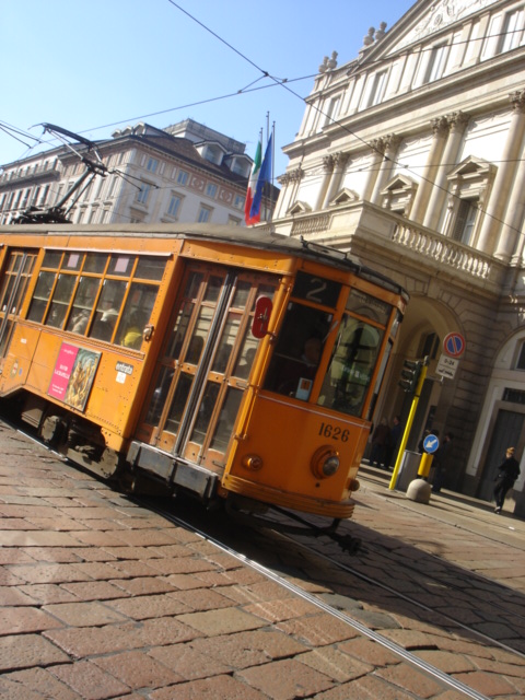 a yellow trolley sitting on the street in front of some buildings