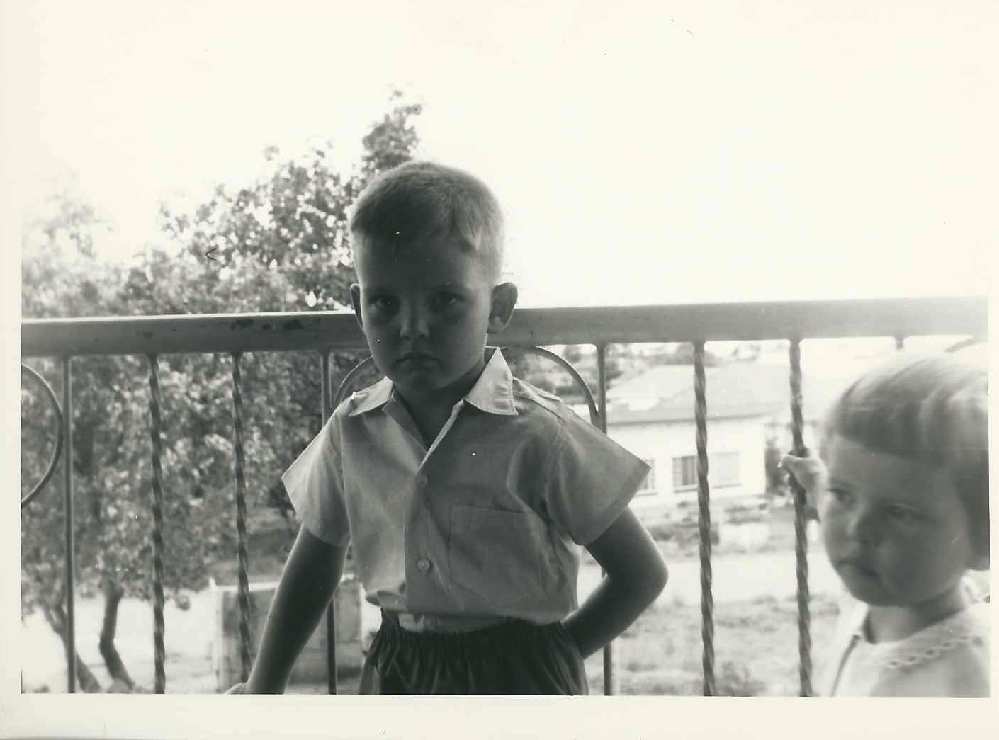 two children standing near each other outside near a fence