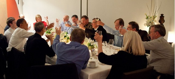 the group of people are toasting at the dinner table