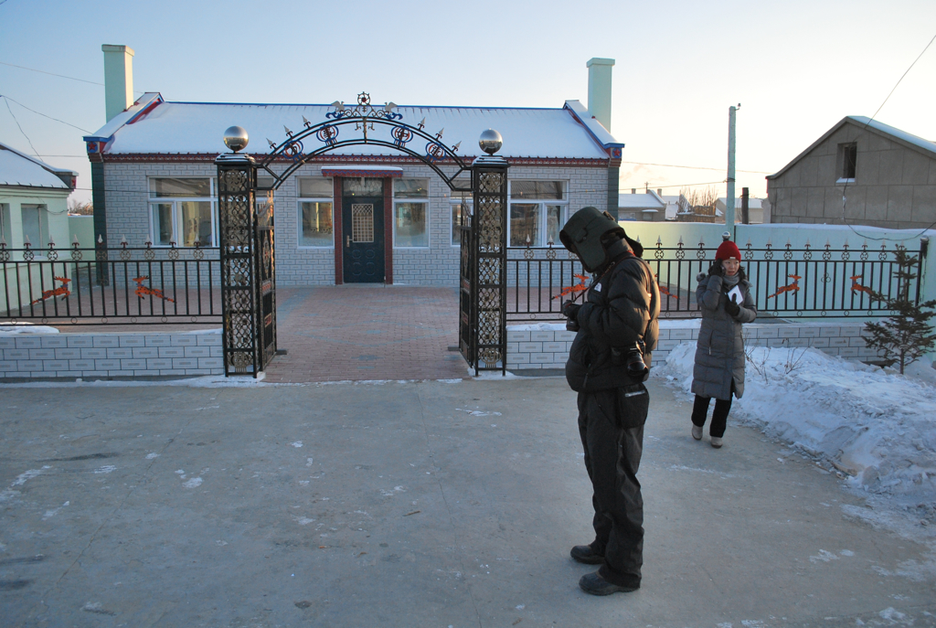 two men standing outside in front of a brick building and gate