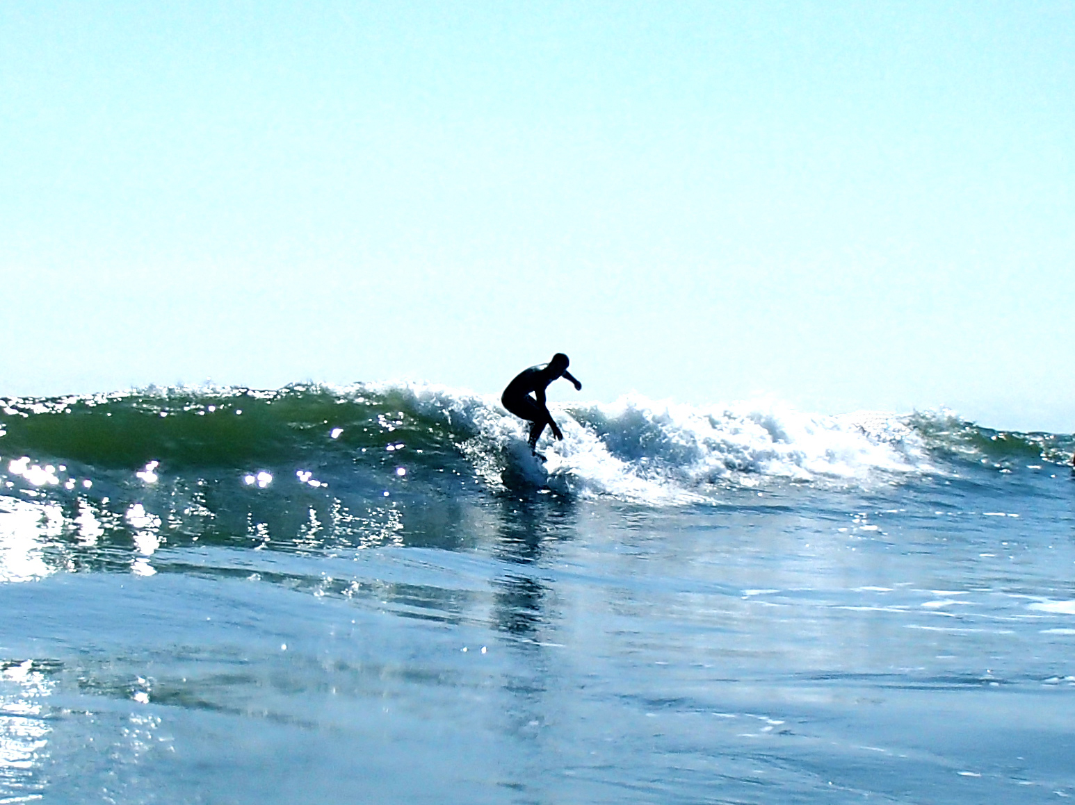 man on surfboard riding small wave in open water