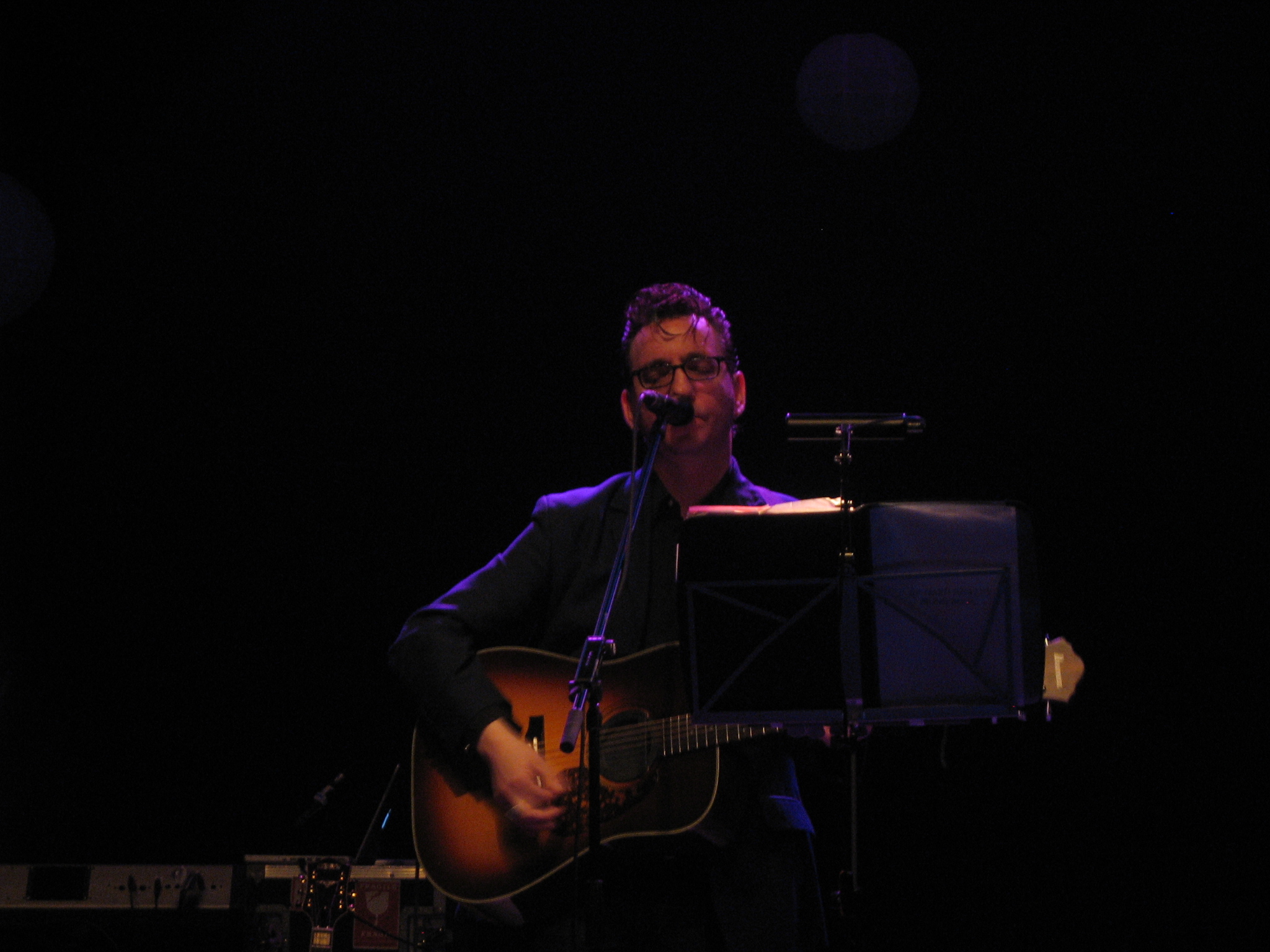 man singing in the dark while playing guitar