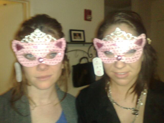 two women with pink and silver maskes standing in a room
