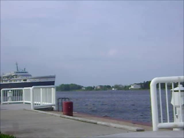 a small boat docked at the pier next to a large body of water