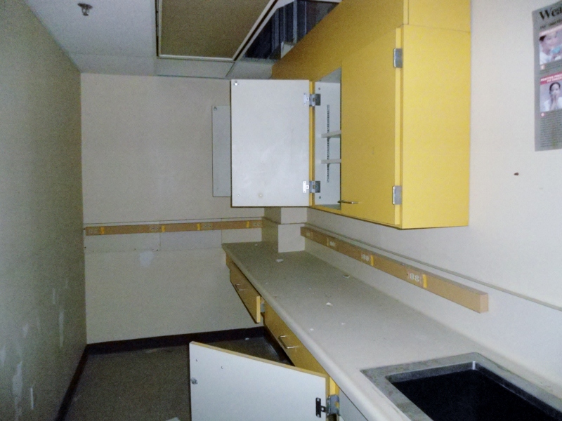 this is a very small kitchen with yellow and white cabinets