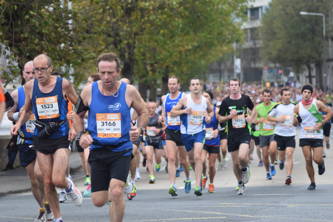 men in bicyclists and runners run down the street