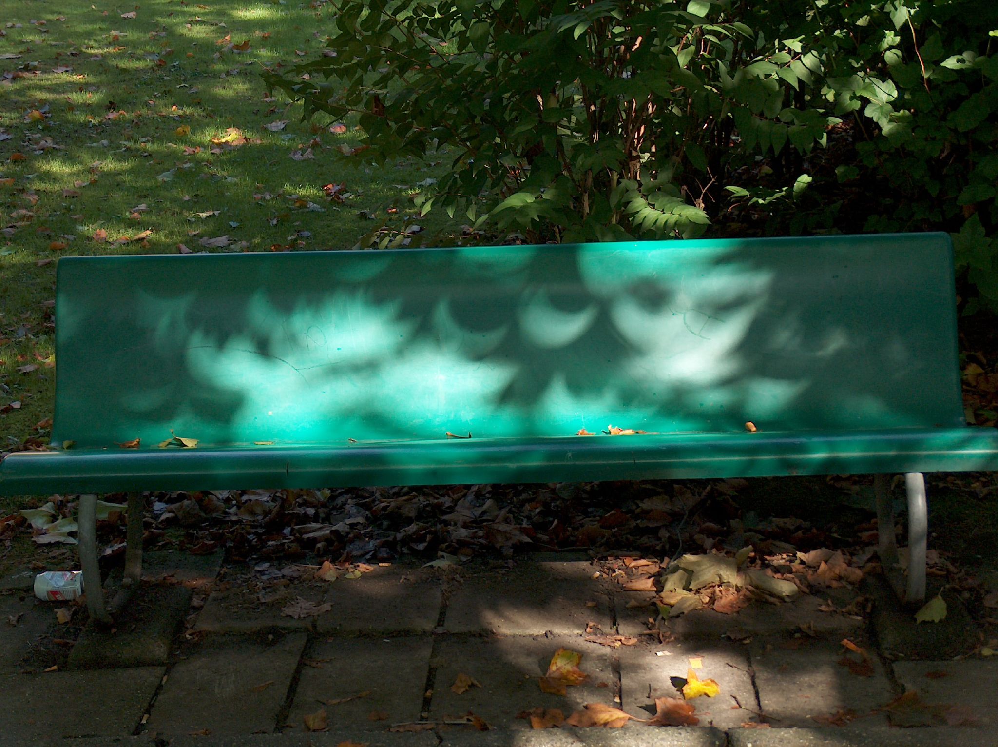 a green park bench in front of some trees