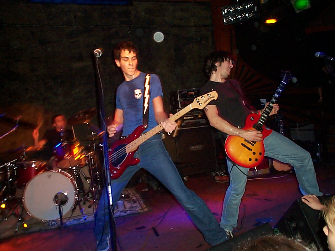 two men are playing guitars on stage in front of an audience