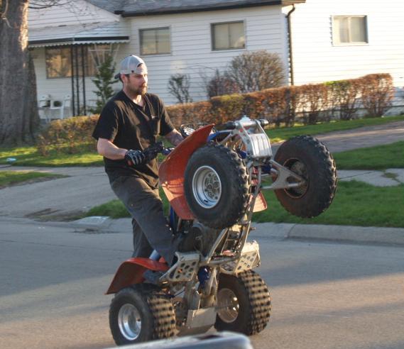 man riding atv on road with large tire