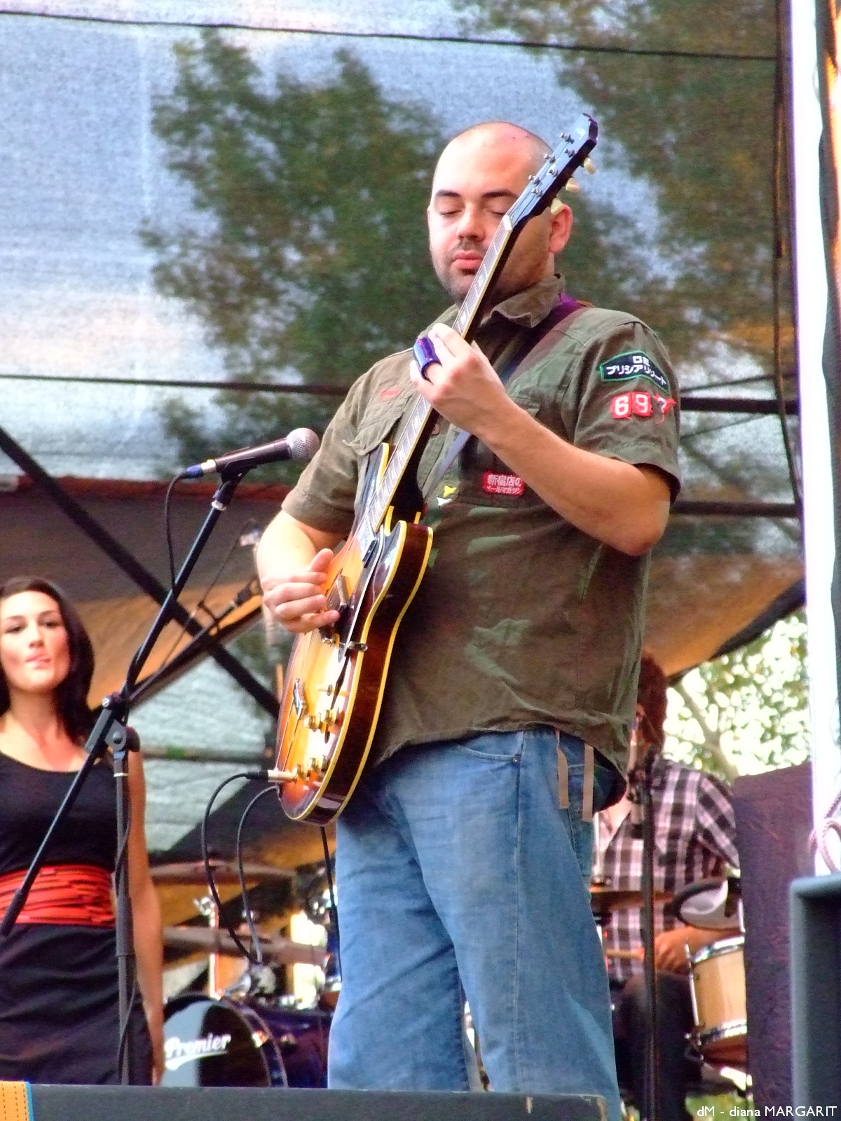a man with a guitar stands in front of some microphones