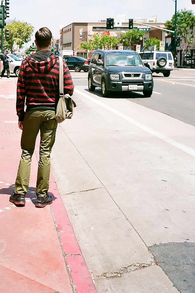 a man walking on the side of a road near a traffic light