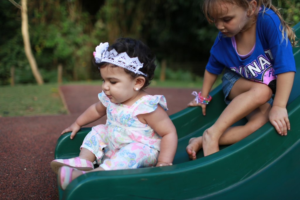 two young children sitting on a green slide