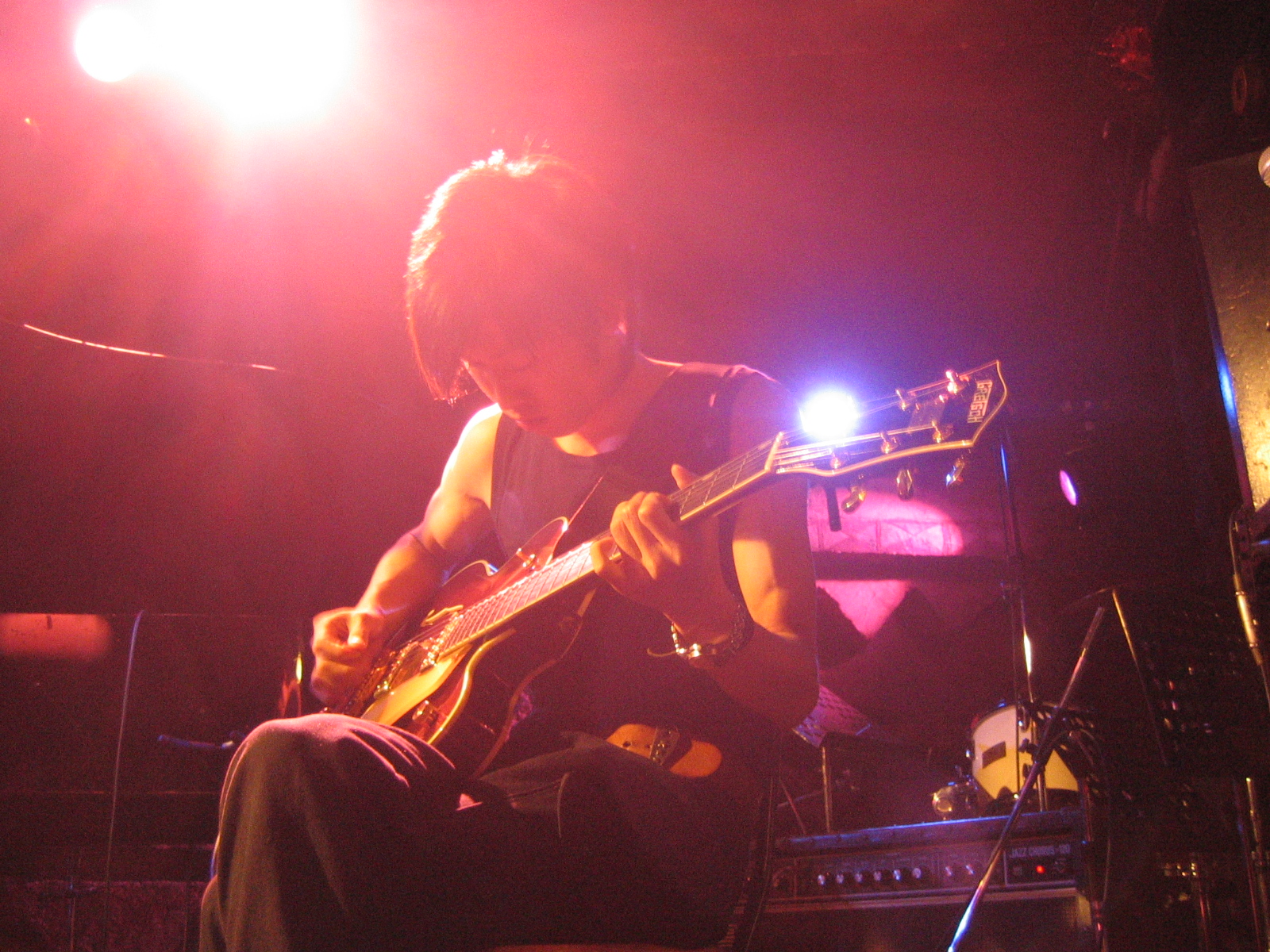 a man sitting on a stool playing an electric guitar