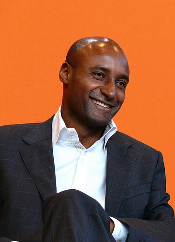 a man smiling while wearing a suit with an orange background