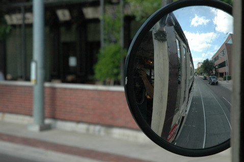 a view of a car mirror on the street with cars