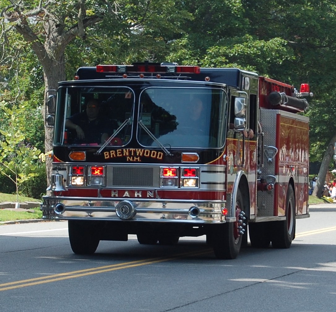 a fire truck traveling on a street next to trees