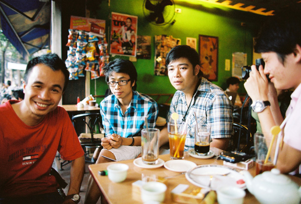 four asian people sitting at the table having food and beverages