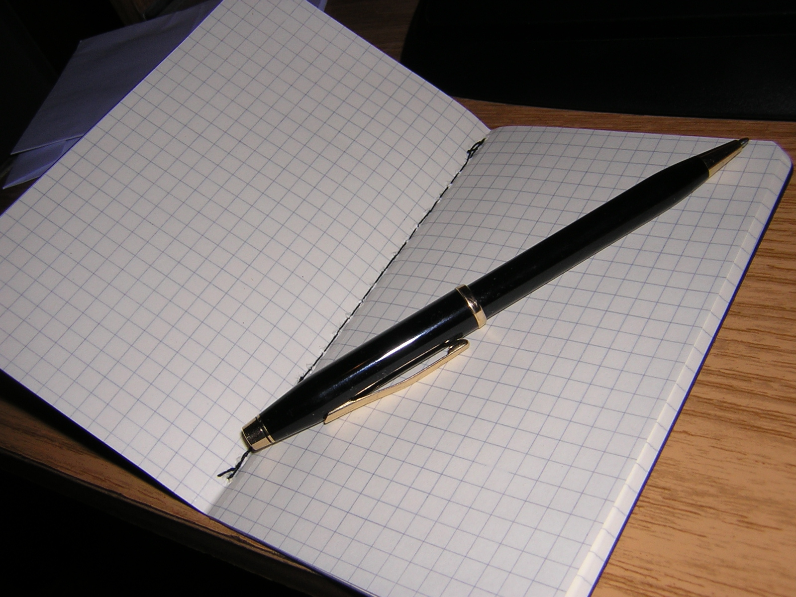 notebook opened with pen, on wood table